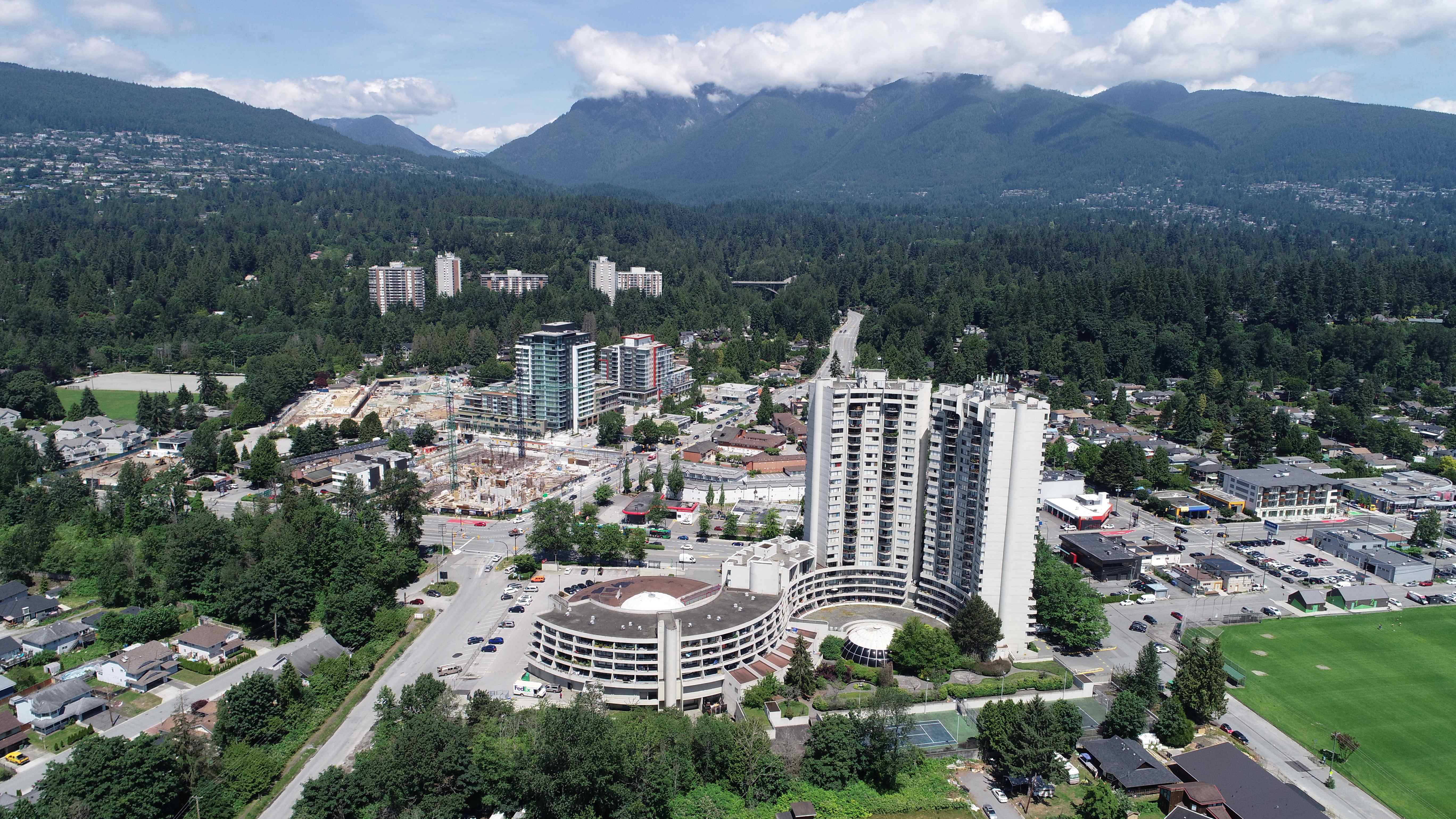A cityscape with a large building in the center and mountains in the background.